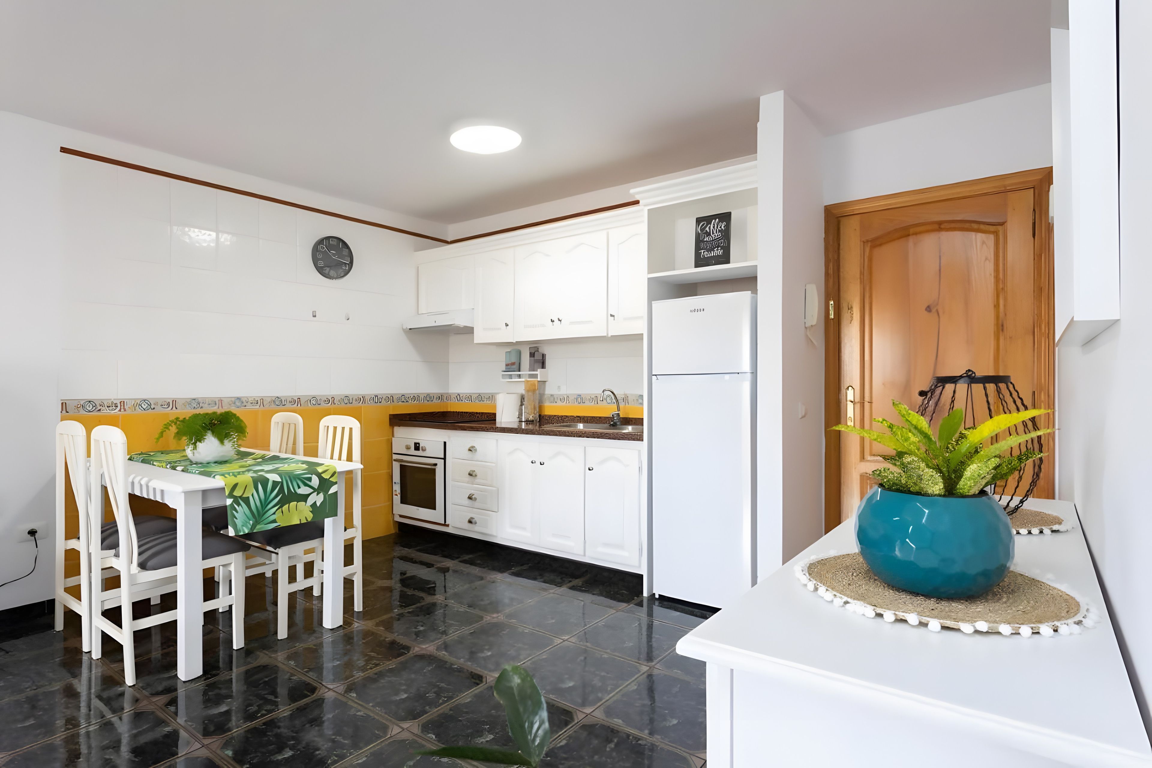 A modern kitchen with white cabinets, a built-in oven, and a refrigerator.