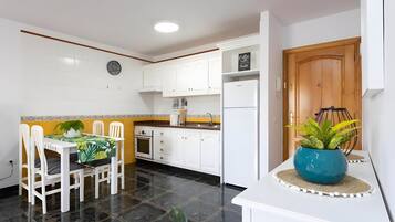 A modern kitchen with white cabinets, a built-in oven, and a refrigerator.
