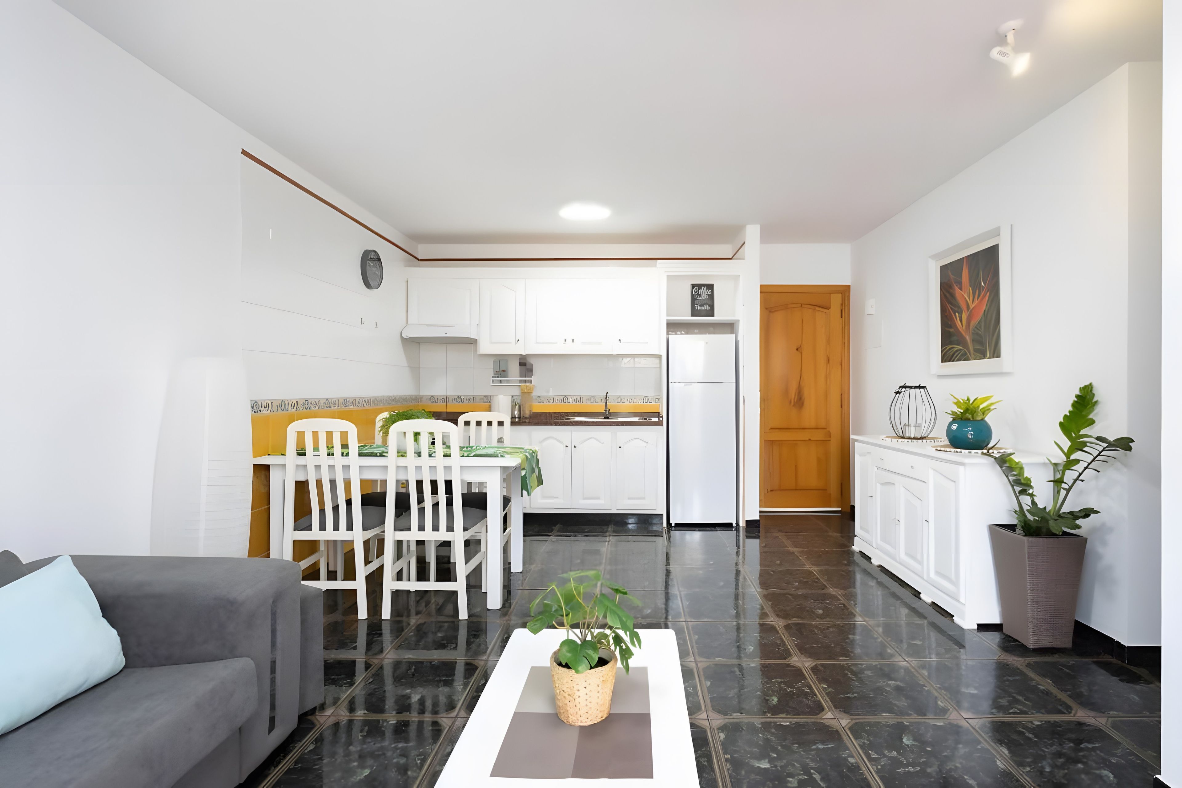 Un espace de vie compact comprenant un coin repas, une kitchenette et un canapé.