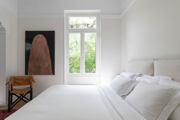 Ein Schlafzimmer mit Bett, Fenster und Stuhl.