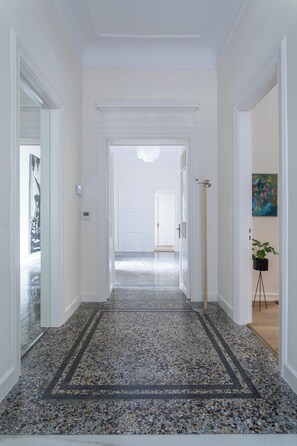 A hallway with a patterned floor, white walls, and a door at the end. - One of Greece’s Most Extraordinary Homes (Athina)