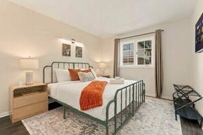 A bedroom with a bed, bedside tables, a window, and a view of the outside. - Cbus Hub · 2 Kings + Loft  2 twin beds · Sleeps 6 · Private Deck & Grill (Columbus)