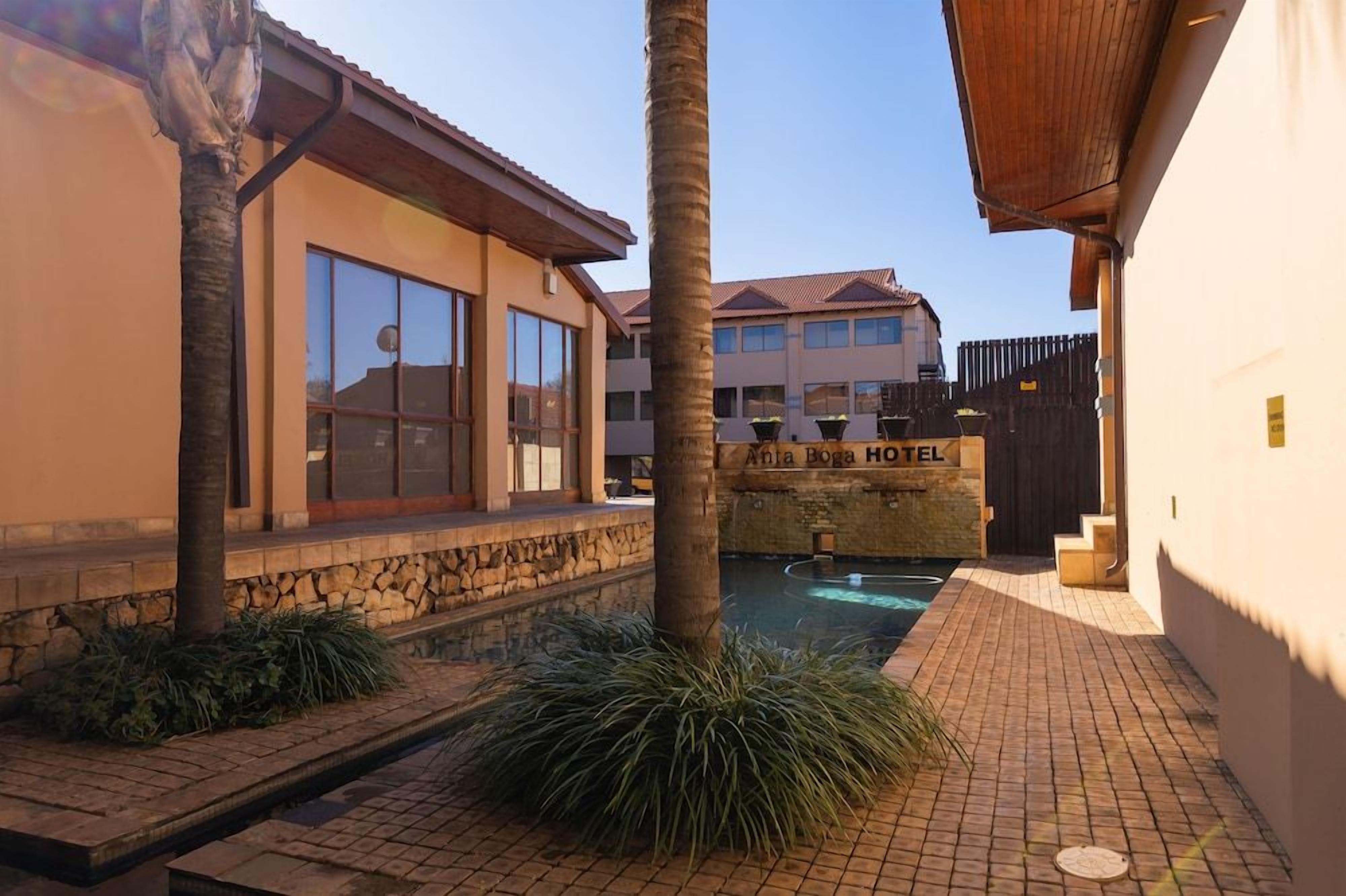 A hotel with a pool, stone walls, and a palm tree.