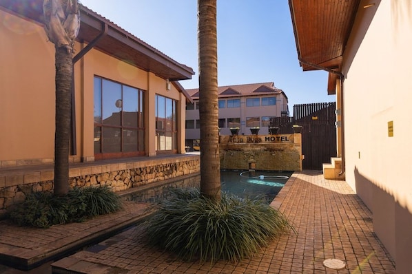 A hotel with a pool, stone walls, and a palm tree. - Anta Boga Hotel (Bloemfontein)