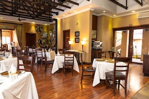 A restaurant with wooden flooring, white tablecloths, and wooden chairs. - Anta Boga Hotel (Bloemfontein)