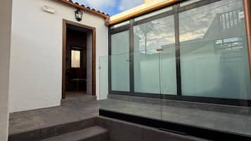 Een gebouw met een trap die leidt naar een glazen deur, een heldere lucht en een pannendak.