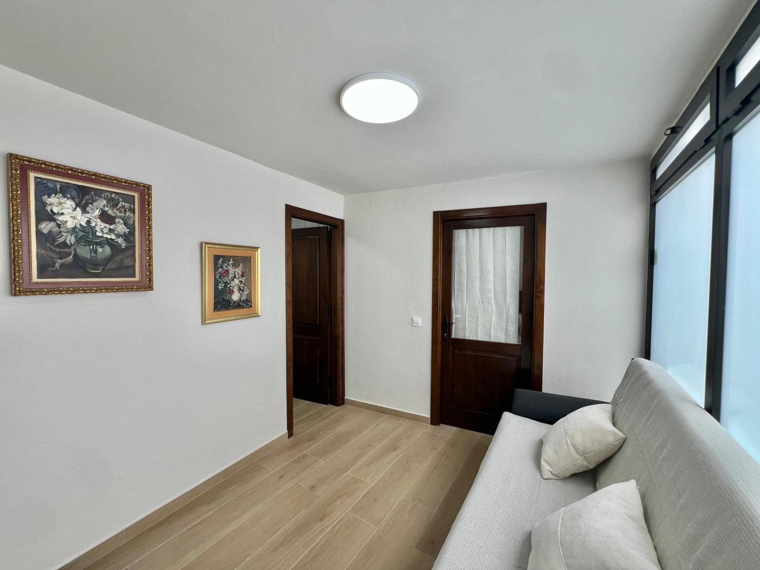 A room with a sofa, a door, and two framed pictures on the wall.