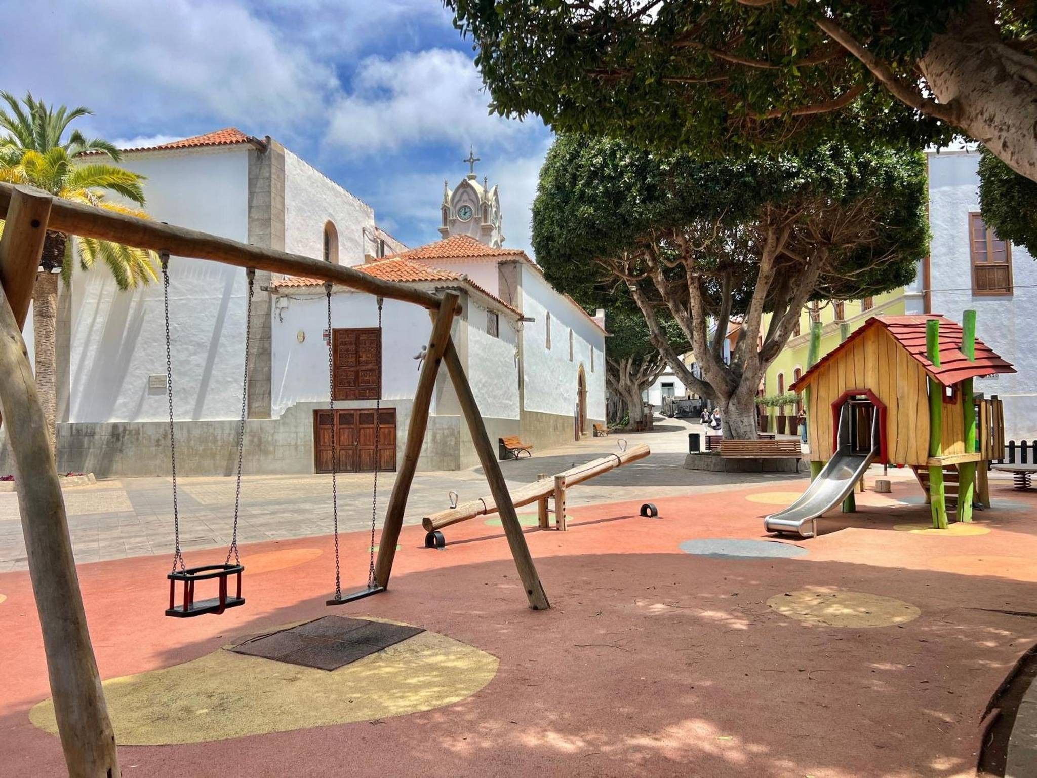 Un parque infantil con columpios, un tobogán y un edificio pequeño.
