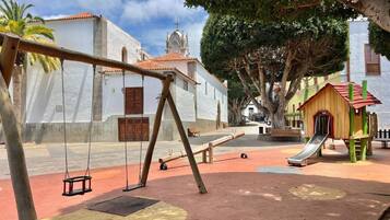 Un parque infantil con columpios, un tobogán y un edificio pequeño.