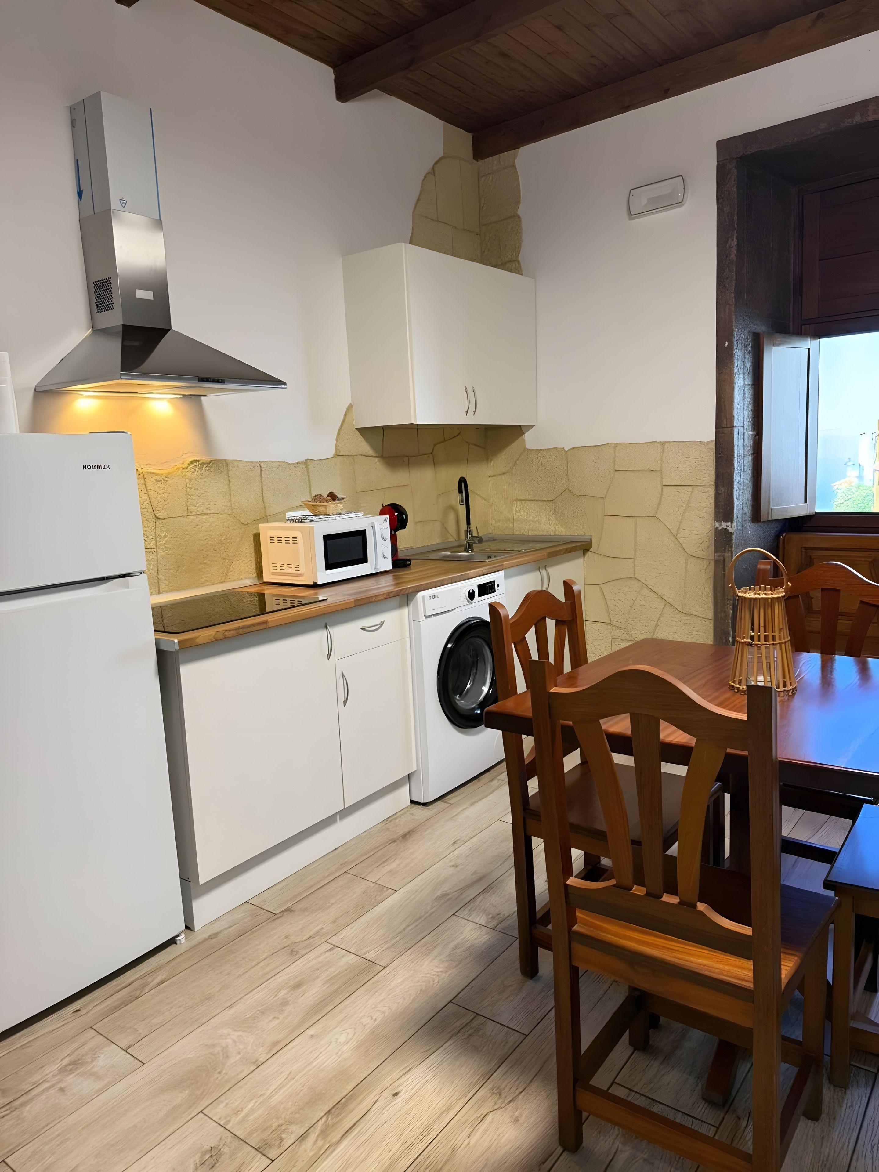 A compact kitchen with a built-in microwave, a toaster, and a washing machine.