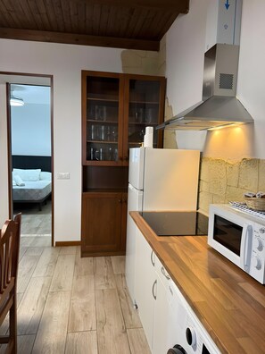 Una cocina compacta con microondas, refrigerador y armarios de madera.