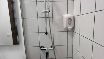 Een badkamer met een douche, een handdroger en een spiegel.