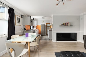 A modern kitchen with a dining area, a fireplace, and a bookshelf. - New! Stylish 2BR Flat near Brockwell Park (Greater London)