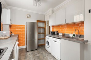 A compact kitchen with a stainless steel refrigerator, a washing machine, and a sink. - New! Stylish 2BR Flat near Brockwell Park (Greater London)