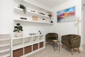 A modern living room with white shelving, a painting, and two armchairs. - New! Stylish 3BR Mews House in Maida Vale (Greater London)