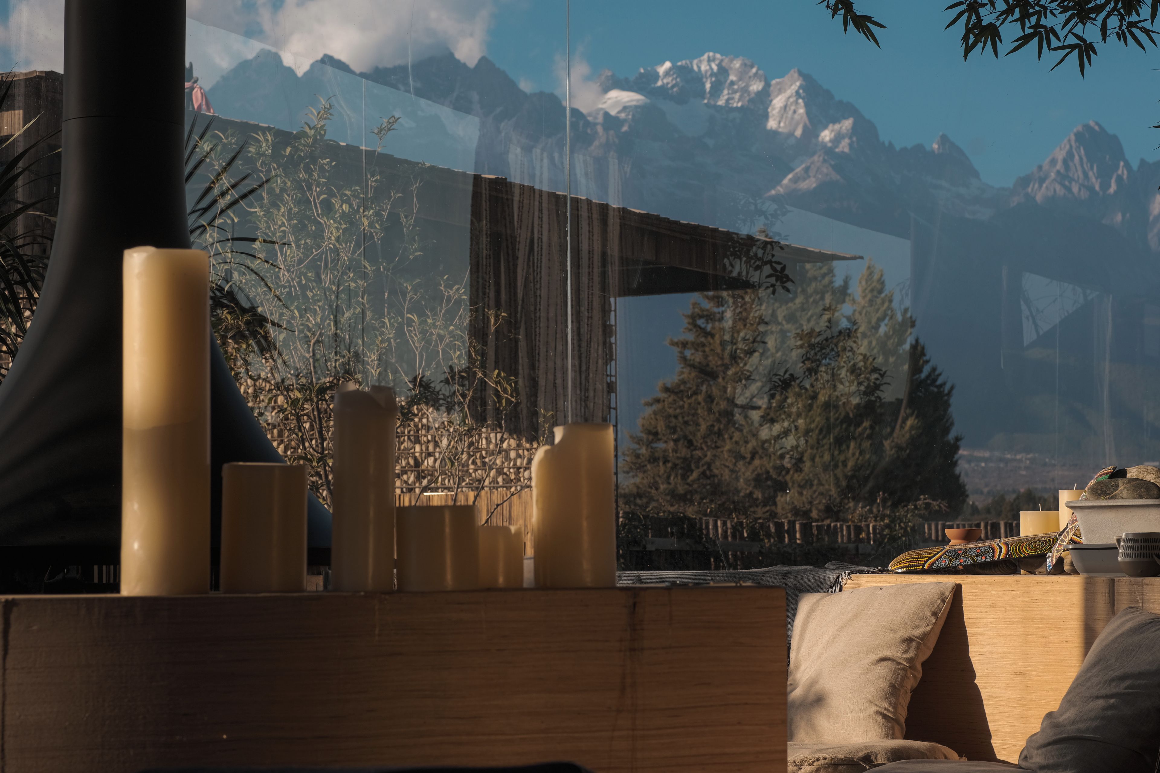 A room with a wooden table, candles, and a view of mountains through a window.