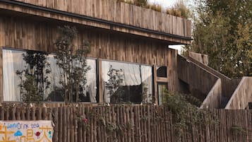 Un edificio moderno con fachada de madera, ventanas amplias y cerca de madera con plantas.