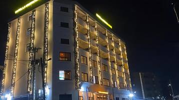 Ein mehrstöckiges Hotel mit Balkonen und einer beleuchteten Fassade bei Nacht.