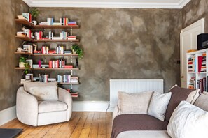 A cozy living room with a sofa, a chair, and a bookshelf filled with books. - Spacious Victorian 2BR by Leith Walk (Edinburgh)