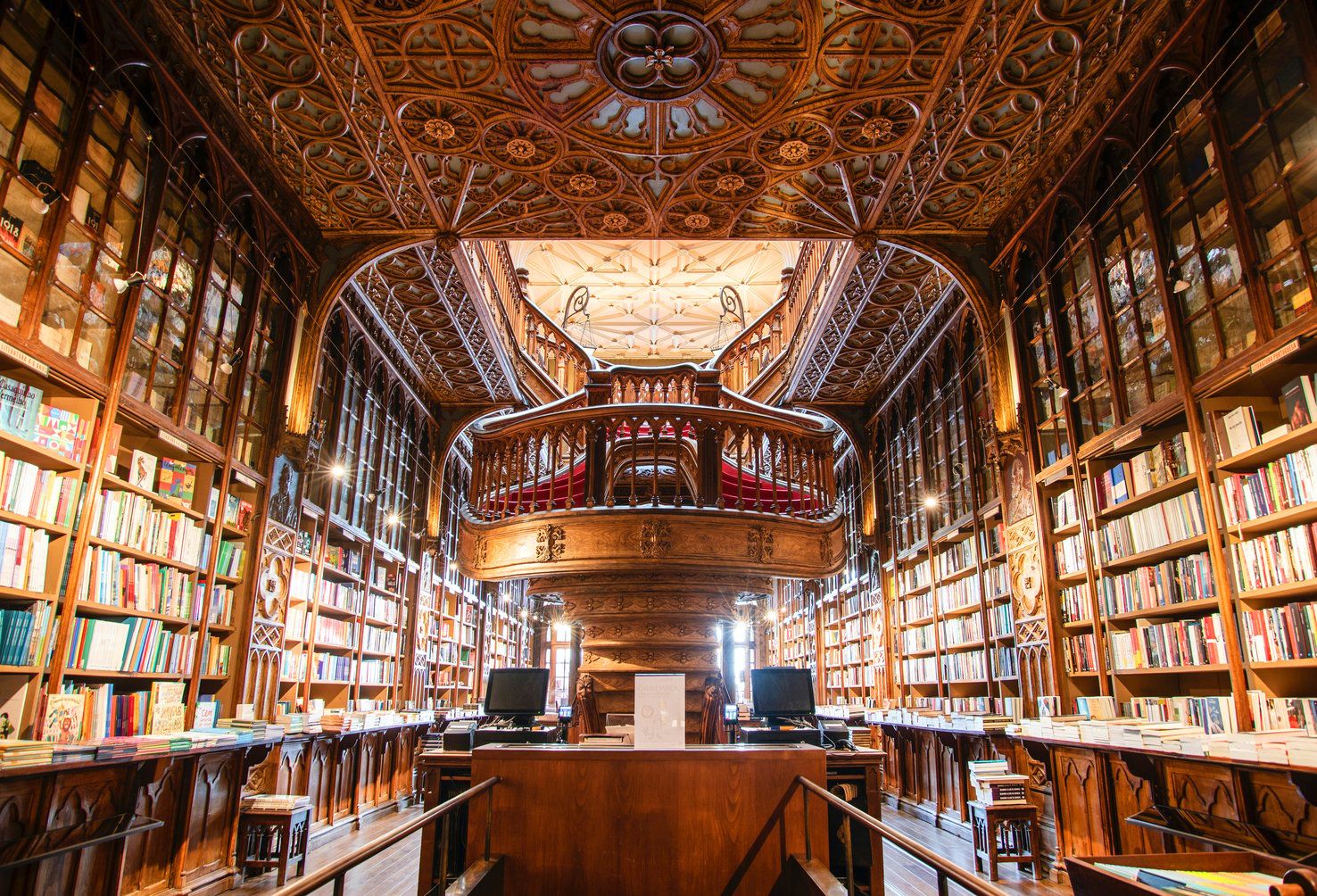Interior de biblioteca con elaborada carpintería, estanterías y una zona central de lectura.