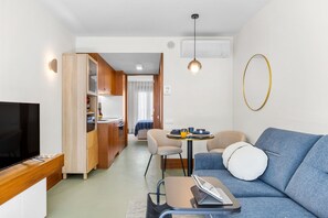 Un espacio habitable funcional con sofá, televisor, comedor y kitchenette.