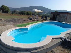 Una piscina de borde curvo, rodeada por una terraza de piedra.