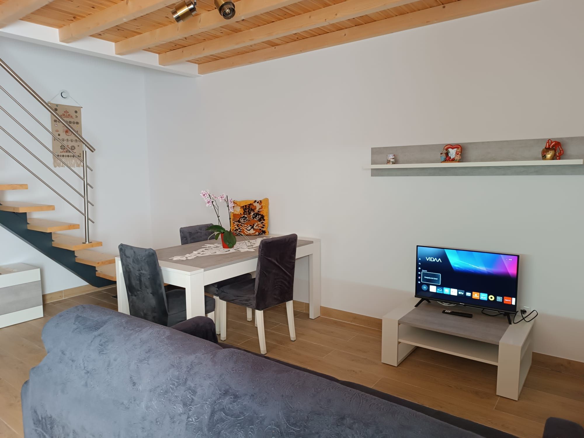 A modern living room with a dining area, a staircase, and a TV on a stand.