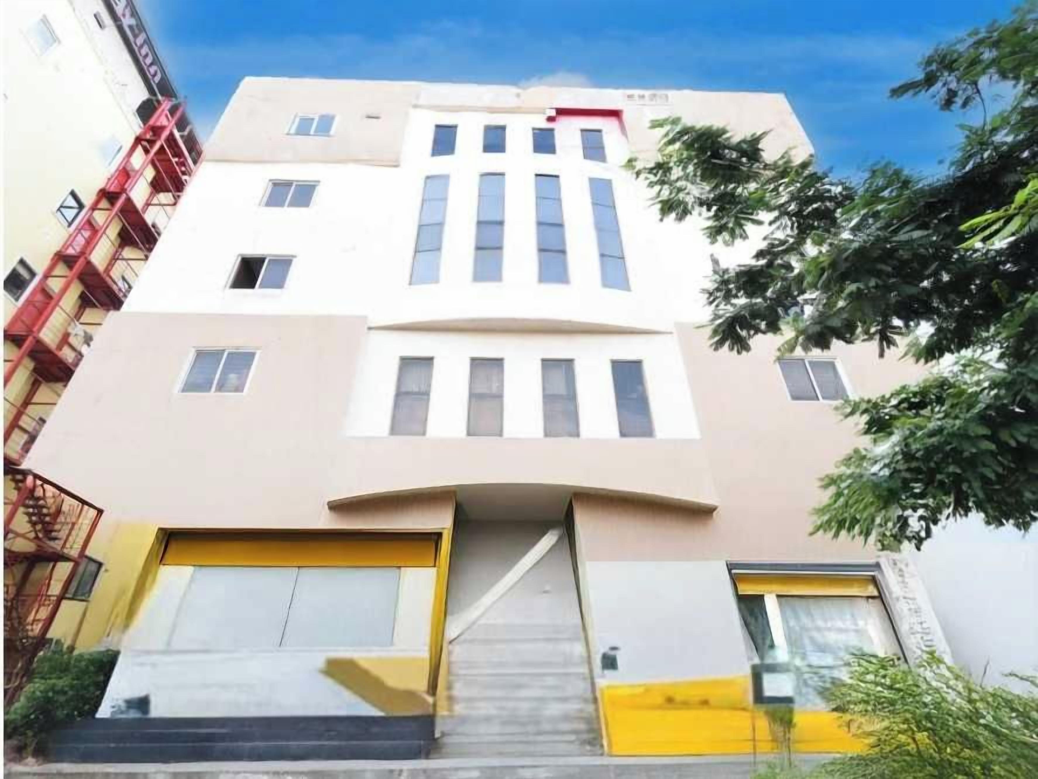 A multi-story building with a central entrance, a fire escape on the left, and a staircase leading to the entrance.