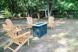 An outdoor seating area with wooden Adirondack chairs and a metal table. - You can bring everybody, have your own rooms, and still actually enjoy being together. (Montgomery)
