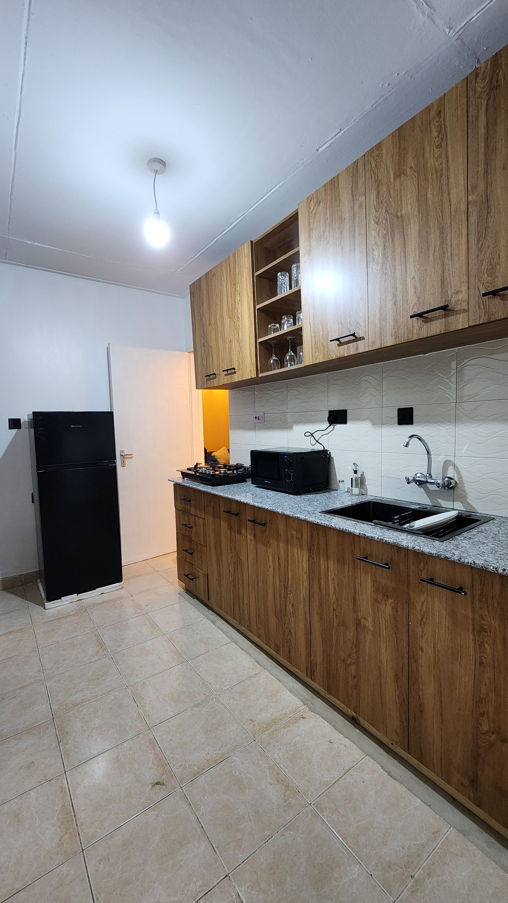 A kitchen with wooden cabinets, a black refrigerator, a microwave, and a gas stove.