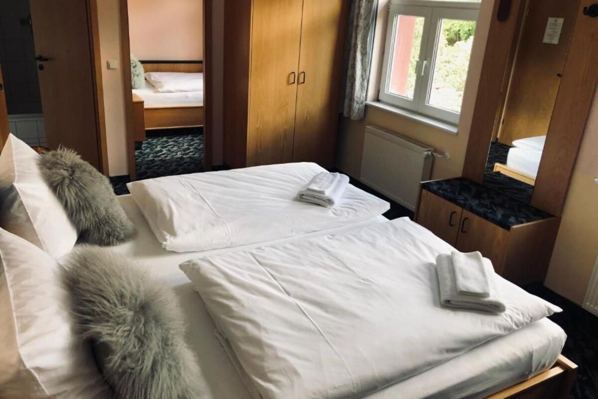 Een hotelkamer met twee bedden, een kledingkast, een tafeltje en een raam met uitzicht.