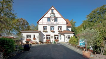 Un hôtel traditionnel, reconnaissable à son enseigne bien visible, à son entrée centrale et à son espace de stationnement.