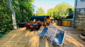 A wooden deck with a barbecue grill, outdoor seating, and a covered area. - Stiefelburg GmbH (Nauendorf)