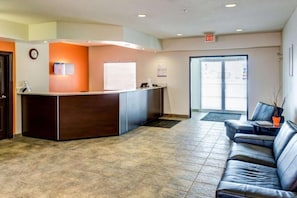 A reception area with a reception desk, a clock, and a seating area with a sofa and a coffee table. - Motel 6 Innisfail AB (Innisfail)