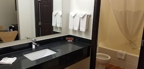 A bathroom with a black countertop sink, a mirror, a toilet, and a shower curtain. - Motel 6 Innisfail AB (Innisfail)