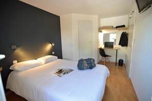 A hotel room with a bed, a desk with a chair, a mirror, and a television. - Fasthotel Limoges (Limoges)