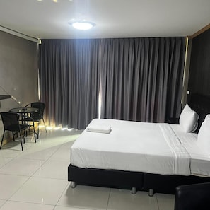 A hotel room with a bed, a desk, a chair, and a large window with curtains. - Apsara INN Pattaya, Thailand (Pattaya)