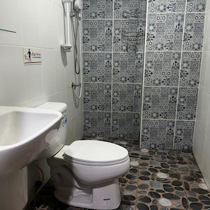 A bathroom with a white toilet, a white sink, and a shower with patterned tiles. - Apsara INN Pattaya, Thailand (Pattaya)