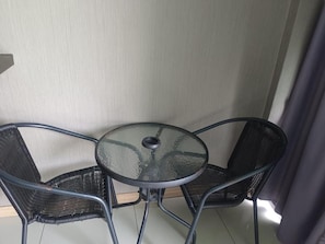 A small round table with a glass top and two black metal chairs. - Apsara INN Pattaya, Thailand (Pattaya)