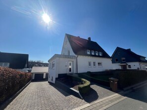 A residential area with a house featuring a sloped roof, a front porch, and a paved driveway. - Apartment 'Hawerländer Auszeit' with Private Terrace, Private Garden and Wi-Fi (Schmallenberg)