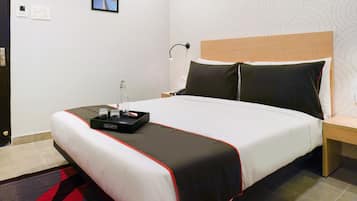 Een hotelkamer met een bed, nachtkastje, lamp en een aan de muur hangend schilderij.