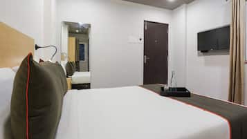 Ein Hotelzimmer mit Bett, Wandfernseher, Tür und Spiegel.