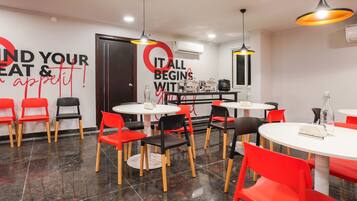 Een restaurantinterieur met ronde tafels en stoelen, een muur met motiverende tekst en hanglampen.