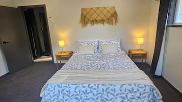 A hotel room with a bed, two bedside tables with lamps, a door, and a wall-mounted decorative item.