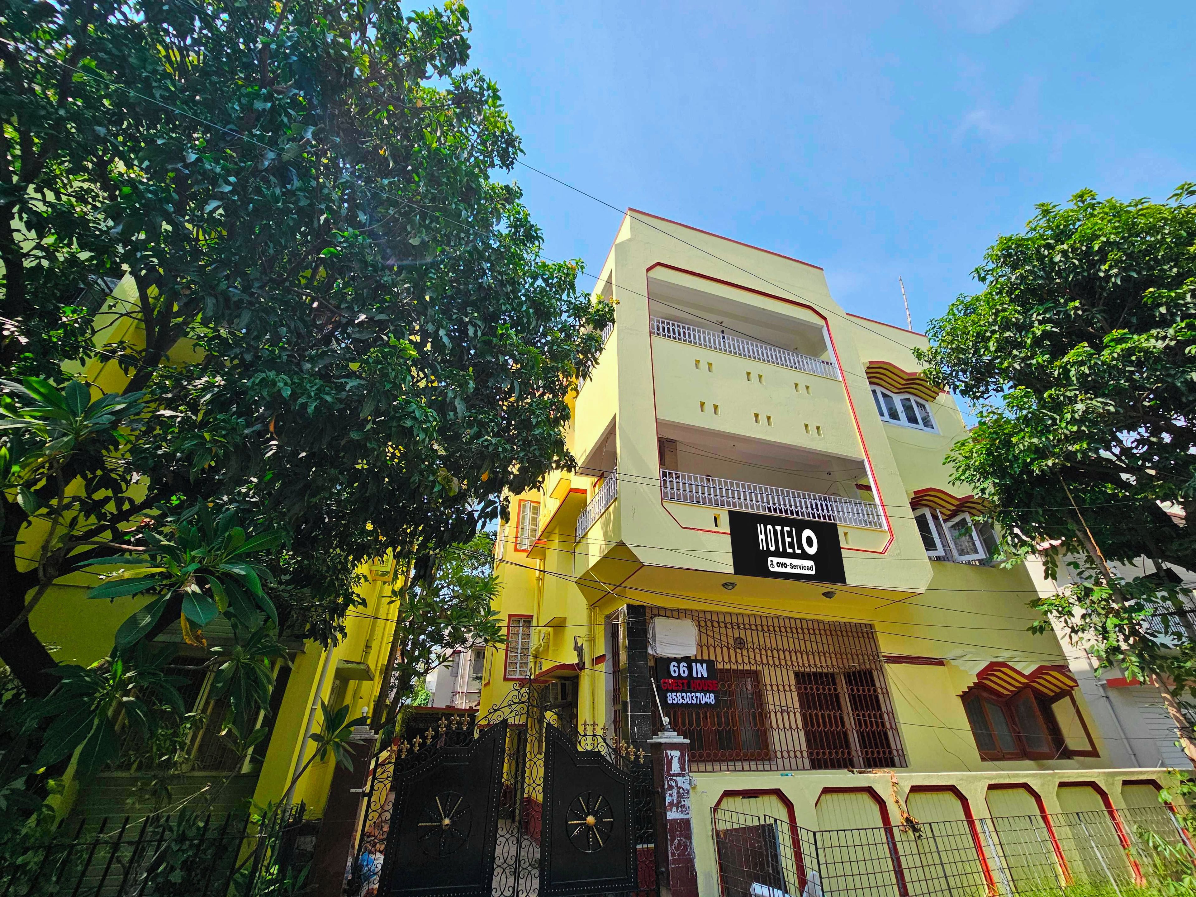 A multi-story hotel with a yellow facade, a balcony on the second floor, and a sign indicating it is serviced by OYO.