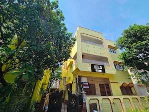 A multi-story hotel with a yellow facade, a balcony on the second floor, and a sign indicating it is serviced by OYO. - Collection O Karunamoyee Salt Lake (Barasat)