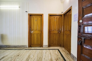 A hallway with two wooden doors, each with a number plate, and a marble-tiled floor. - Collection O Karunamoyee Salt Lake (Barasat)