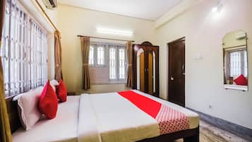 Una habitación de hotel con cama, cortinas, ventana, aire acondicionado y ventilador de techo.