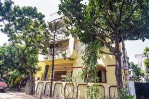 A two-story building with a yellow facade, a gated entrance, and a balcony.
