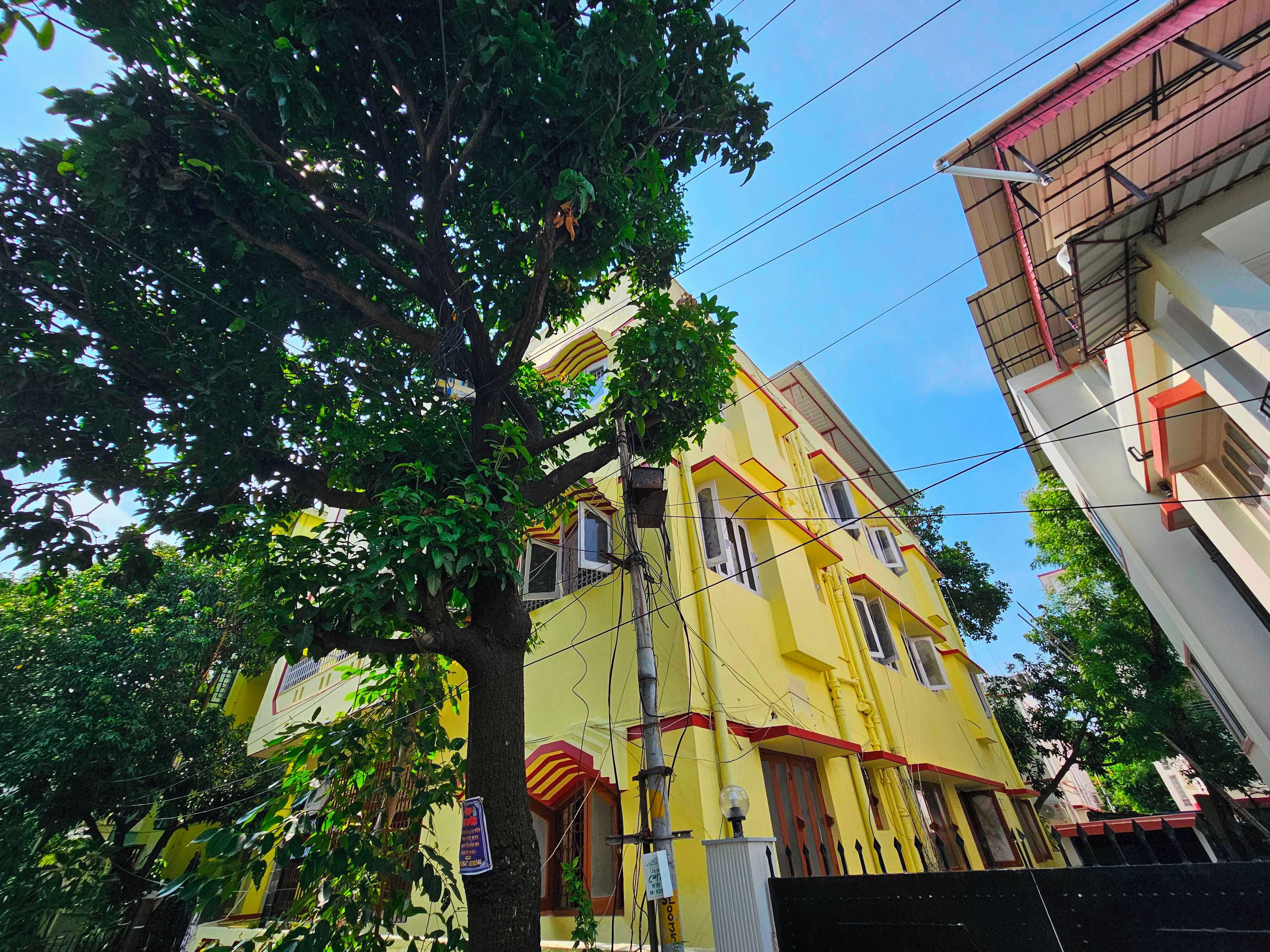 Un edificio de varios pisos con fachada amarilla, múltiples ventanas y un balcón visible.